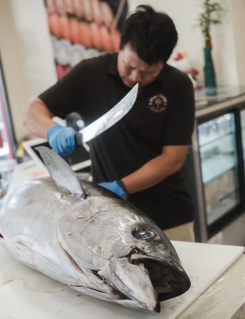 One of the owners of Domo Cafe breaking down a whole tuna at the counter