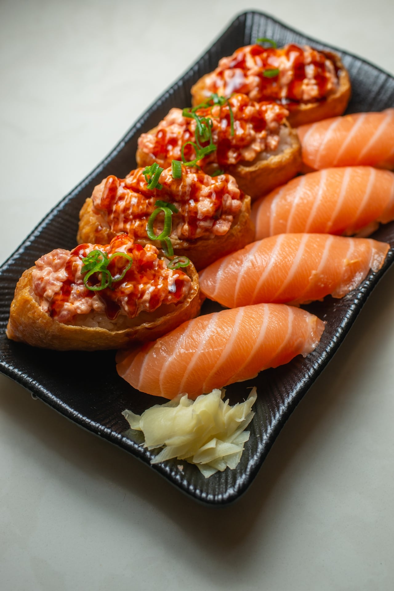 Salmon nigiri and spicy ahi gunkan on a black plate